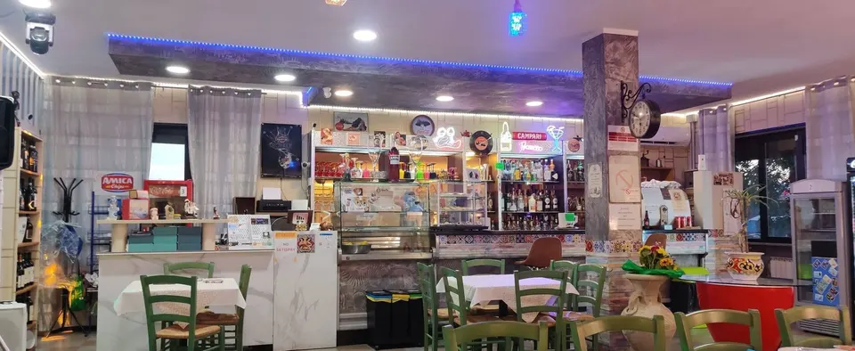 Il bancone del bar con la vetrina e le sedie verdi
