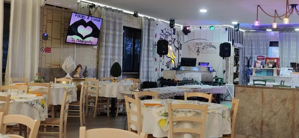 La sala con i tavoli rotondi e la postazione DJ